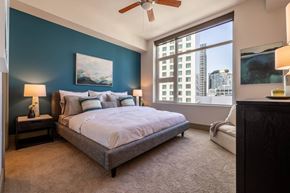 Seattle apartment for rent - A bedroom with a bed, a ceiling fan, and a window overlooking a cityscape.