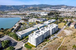 San Francisco apartment for rent - A large white building with a circular courtyard in the middle is surrounded by a parking lot and other buildings.