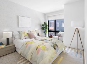 New Rochelle apartment for rent - A bedroom with a bed, a lamp, a plant, and a picture on the wall.
