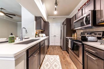 Houston apartment for rent - A modern kitchen with dark brown cabinets and stainless steel appliances.