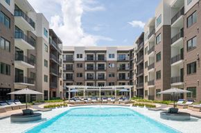 Houston apartment for rent - A large swimming pool surrounded by apartment buildings and lounge chairs.