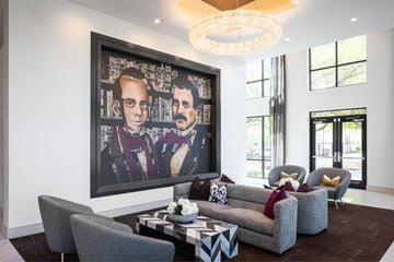 Houston apartment for rent - A living room with a large painting of two men, a grey sofa, and a coffee table.