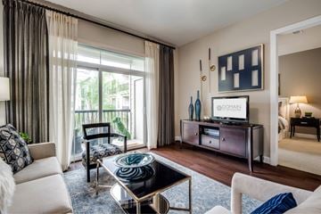 Houston apartment for rent - A living room with a white sofa, a glass coffee table, and a television on a cabinet.