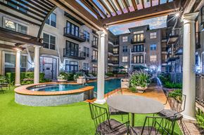 Houston apartment for rent - A patio with a table and chairs overlooking a pool.