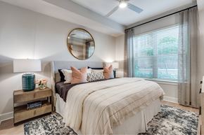 Houston apartment for rent - A bedroom with a large bed and a round mirror on the wall.