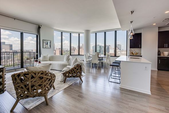 Houston apartment for rent - A modern living room with a white sofa and a wooden chair.