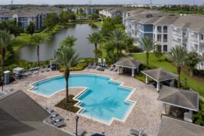 Orlando apartment for rent - A swimming pool surrounded by palm trees and apartment buildings.