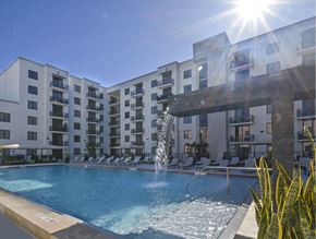 Miami apartment for rent - A sunny day at a pool with a fountain in the middle of it.