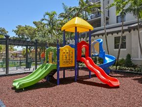 Miami apartment for rent - A playground with a yellow umbrella and a slide that says "cool" on it.