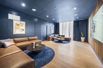 Miami apartment for rent - A modern living room with a brown leather sofa and a blue rug.