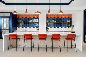 Miami apartment for rent - A kitchen with a white counter and orange chairs.
