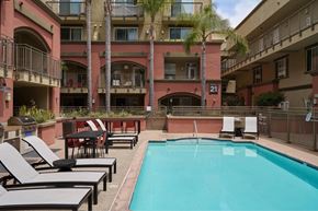 San Diego apartment for rent - A pool surrounded by lounge chairs and palm trees.