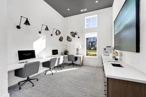 Matthews apartment for rent - A modern office space with white desks and chairs, a large screen on the wall, and a view of the outside through a window.