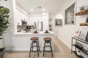 Peoria apartment for rent - A kitchen with white cabinets and a white countertop with two stools in front of it.