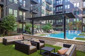 Dallas apartment for rent - A patio with a pool and a black umbrella.