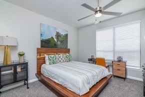 Dallas apartment for rent - A bedroom with a bed, nightstand, and a painting on the wall.