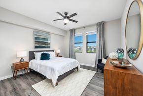 Pembroke Pines apartment for rent - A bedroom with a large bed, a ceiling fan, and a view of the outdoors through the window.