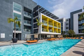 Marina Del Rey apartment for rent - Modern building complex with a pool and lounge chairs.