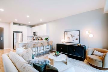 Kansas City apartment for rent - A modern living room with a white sofa, a black cabinet, and a dining table with chairs.