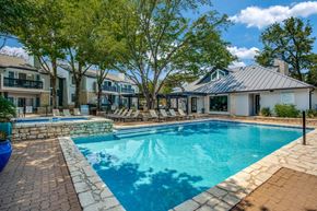 Austin apartment for rent - A swimming pool surrounded by a stone patio and lounge chairs.