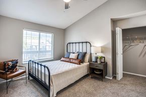 Austin apartment for rent - A bedroom with a bed, chair, and a window.