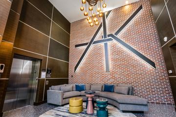 Dallas apartment for rent - A modern living room with a grey couch and a brick wall.