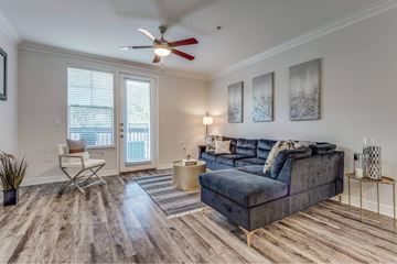 Houston apartment for rent - A living room with a blue couch and a ceiling fan.