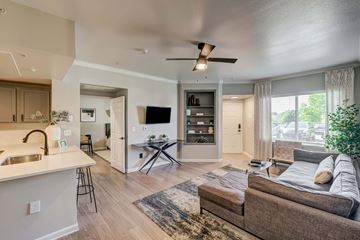Aurora apartment for rent - A modern living room with a brown couch and a white kitchen area.