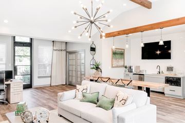 Rockwall apartment for rent - A white couch with green pillows sits in a living room with a wooden floor and a chandelier hanging from the ceiling.
