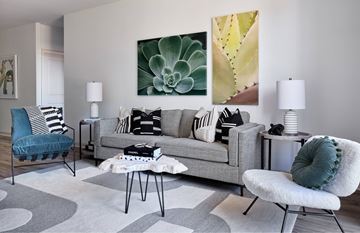 Raleigh apartment for rent - A living room with a grey couch, a blue chair, and a painting on the wall.