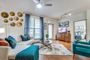 Carrollton apartment for rent - A living room with a white couch, a blue chair, and a rug with a pattern.
