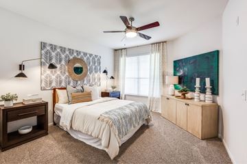Pearland apartment for rent - A bedroom with a bed, a ceiling fan, and a painting on the wall.