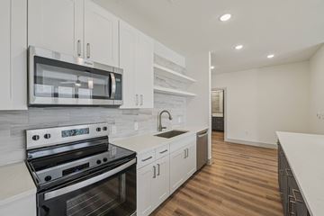 Garland apartment for rent - A modern kitchen with a black stove top oven and white cabinets.