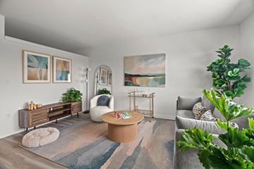 Seattle apartment for rent - A living room with a grey couch, a white chair, a wooden coffee table, and a painting on the wall.