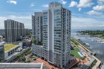Stamford apartment for rent - A modern high-rise building with a green roof is situated next to a body of water with boats docked.