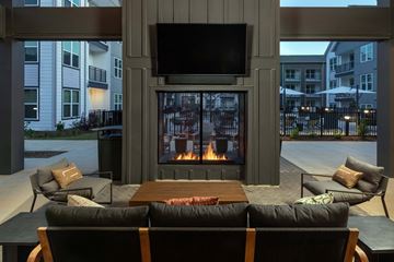 Raleigh apartment for rent - A modern living room with a fireplace and a television mounted above it.