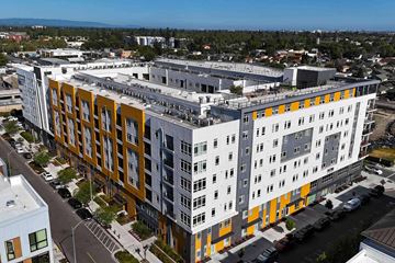San Jose apartment for rent - A modern multi-story building with a combination of white and orange panels.