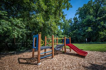 Fairfax apartment for rent - A playground with a red slide and a blue and yellow climbing frame.