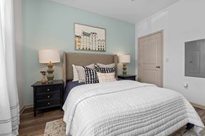 Charlotte apartment for rent - A bedroom with a large bed, two lamps, and a painting on the wall.