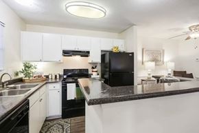 Norcross apartment for rent - A black refrigerator is in a kitchen with white cabinets.