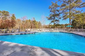 Norcross apartment for rent - A large swimming pool surrounded by a white fence and trees.