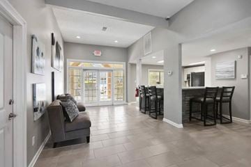 Norcross apartment for rent - A spacious living room with a grey couch and a bar area with stools.