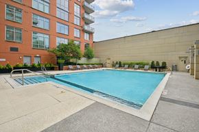 Reston apartment for rent - A large swimming pool in front of a red brick building.