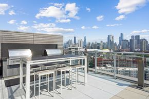 Chicago apartment for rent - A rooftop patio with a table and chairs overlooking a city skyline.