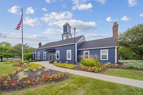 Indianapolis apartment for rent - A blue building with a bell tower and a flag on a sunny day.