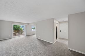 Indianapolis apartment for rent - A spacious room with a carpeted floor and a door on the right side.