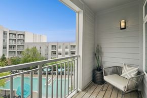 Rockville apartment for rent - A balcony with a chair and a potted plant overlooks a pool and apartment building.