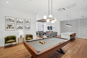 Beverly apartment for rent - A pool table is in the middle of a room with a green chair and pictures on the wall.