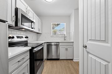 Pooler apartment for rent - A kitchen with white cabinets and black appliances.