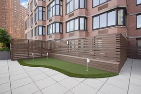 New York apartment for rent - a wooden fence around a putting green in front of a brick building
